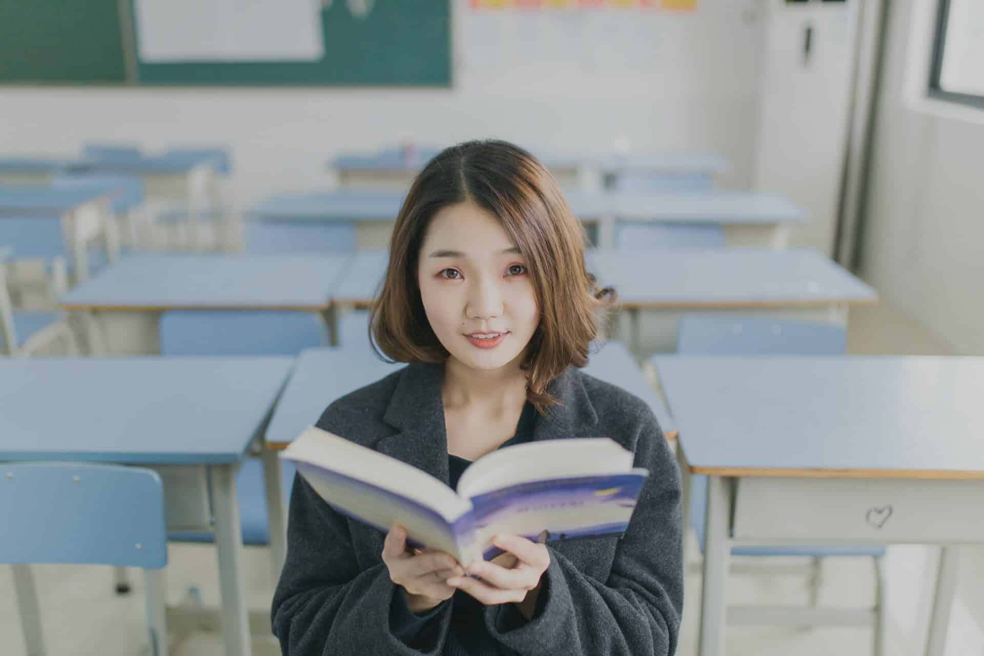 A lady sitting in a classroom with an open book